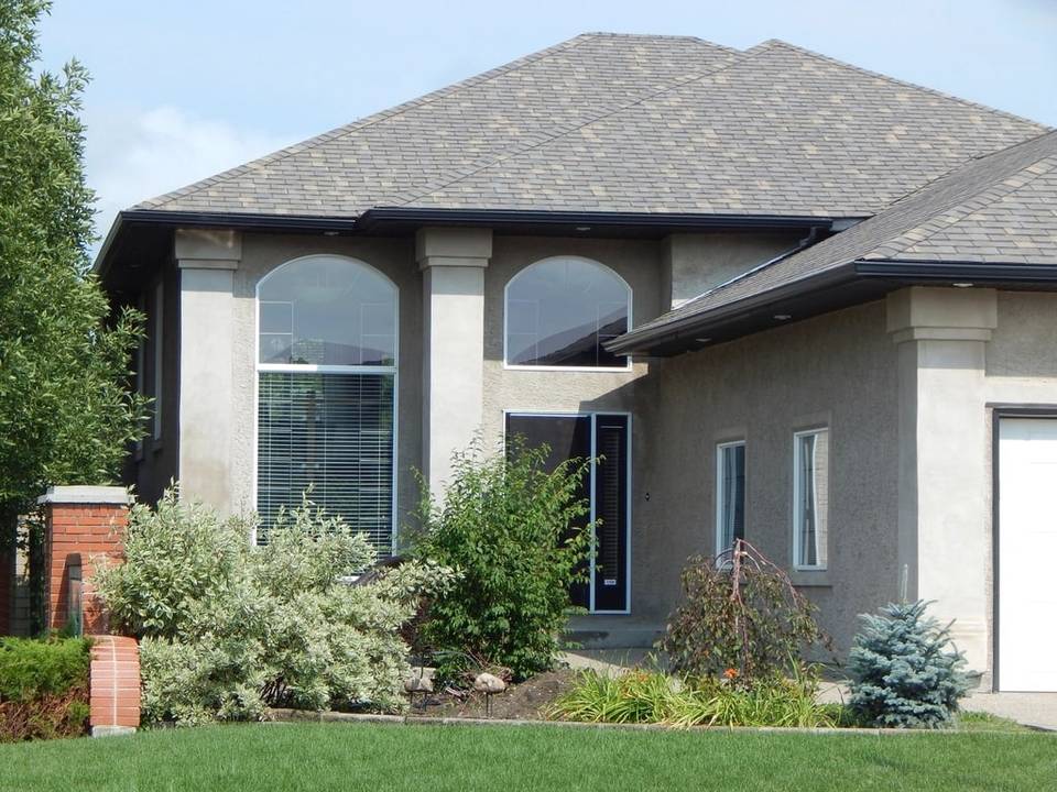 Two-story stucco house with arched windows and landscaping